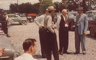 Great Grandfather 'Dad' (in the vest and red tie) holding conversational court in the church parking lot. To his left, the teacher at the one-room Big Ridge schoolhouse.