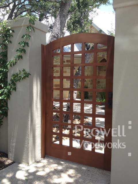Site photograph showing the arching wood Gate 27 in Austin,Texas between stucco columns